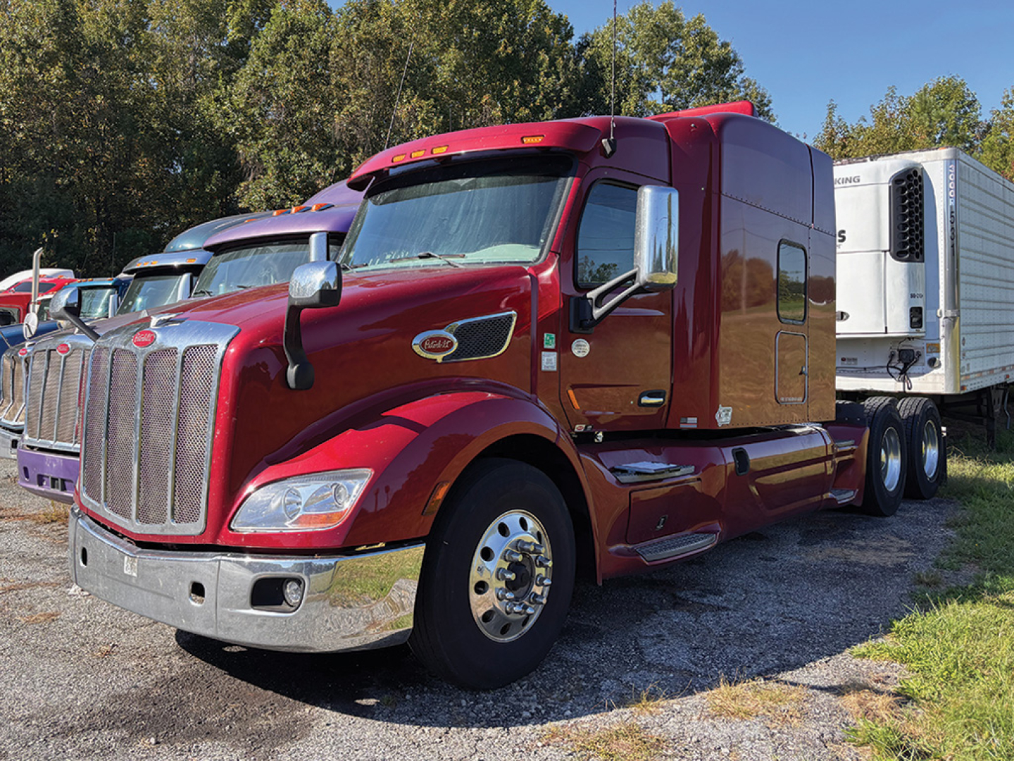 Truck image: red Peterbilt 579 UltraCab tractor with chrome grille and large sleeper, parked next to a refrigerated trailer.