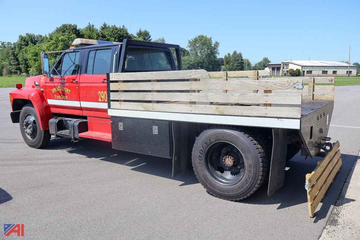 Ford F-7000 stake bed truck side view showing wooden stake sides and flatbed with tool storage box and rear bumper.