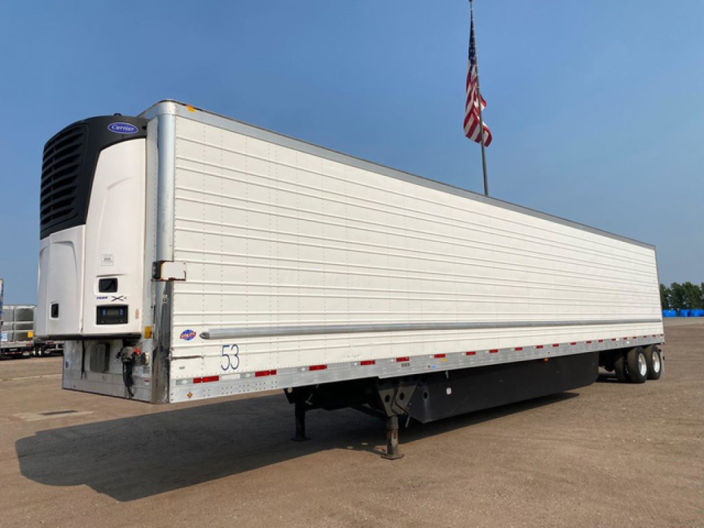Trailer side view showing a white refrigerated utility trailer with a Columbia R360X or similar reefer unit at the front, VIN tag and stock number placard visible.