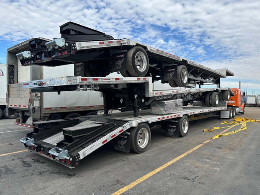 Manac combo drop deck trailer stack showing multiple axles and folded drop sections with a spare wheel and ramps, new equipment.