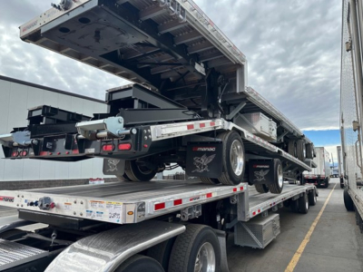 Manac combo drop deck trailer on a multi-axle trailer with rear deck raised, showing steel frame, wheels, and reflective tape.