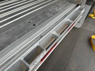 Manac combo drop deck trailer edge with aluminum deck and stake pockets visible.