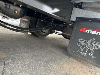 Manac combo drop deck trailer undercarriage showing suspension and hydraulic lines with Manac branding.