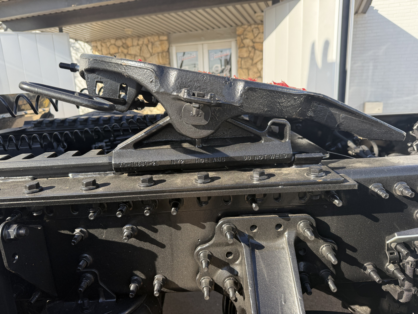 Mack PR64T truck cab area showing chassis with linkage and a raised air deflector/landing pad on top of frame rail, multiple bolts and metal brackets visible.