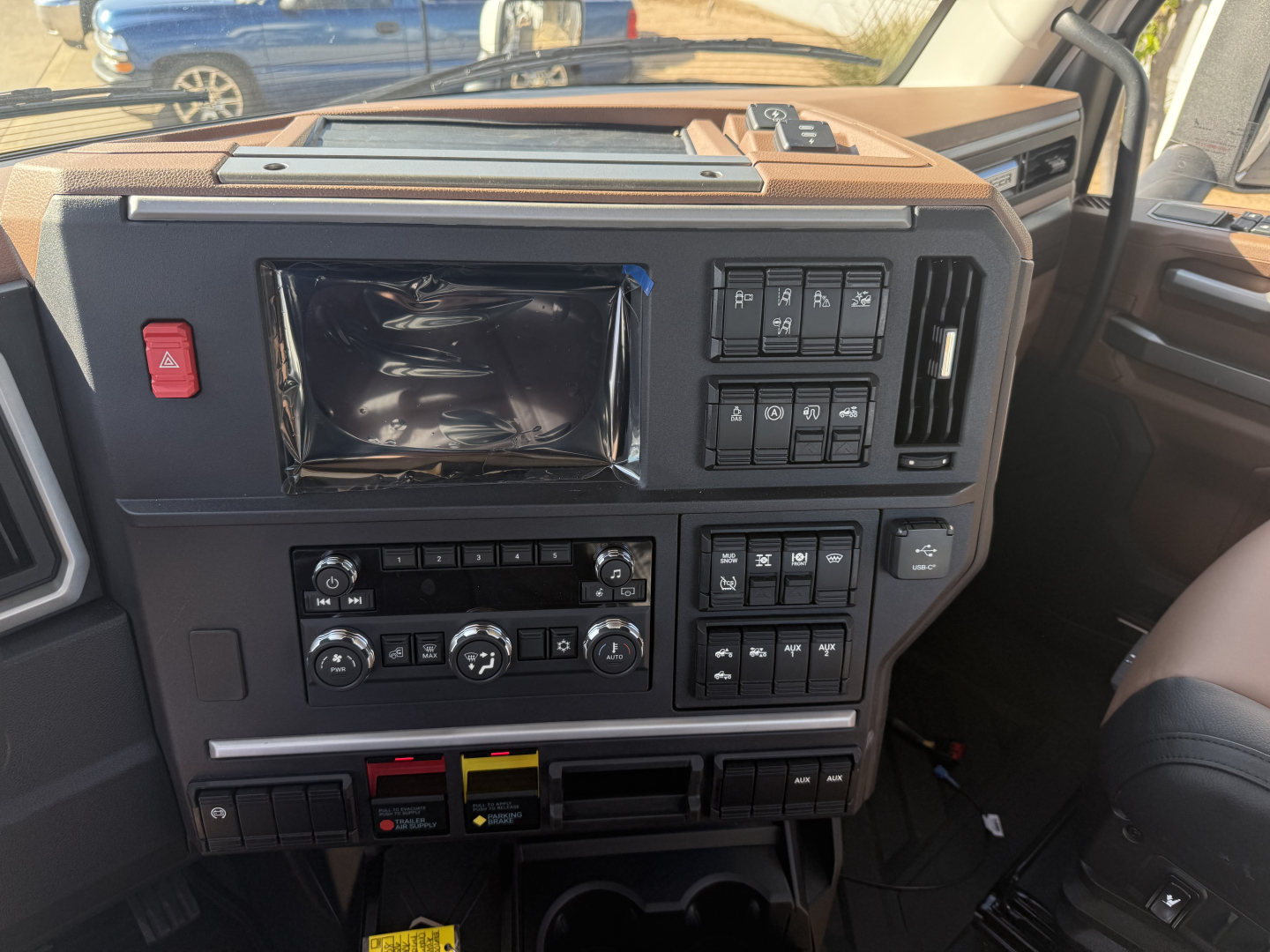 Cab interior of a 2026 Mack PR64T showing dashboard controls, infotainment screen, climate controls, and switch panels.