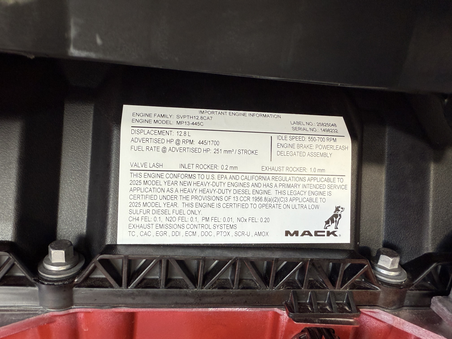 Engine information label on Mack PR64T showing engine family, displacement, fuel rate, and other specs.