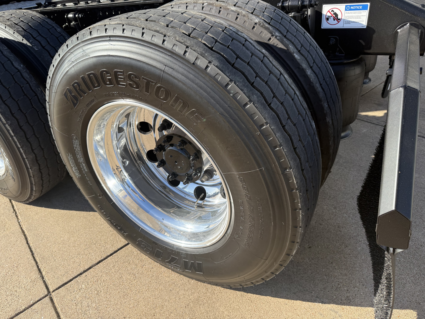 Bridgestone front dual rear tires on a Mack PR64T conventional daycab truck showing chrome wheel and suspension components.
