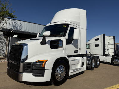 Truck cab and sleeper daycab tractor showing Mack emblem on black grille, headlights, white exterior, chrome wheels, fuel tanks, and side steps.