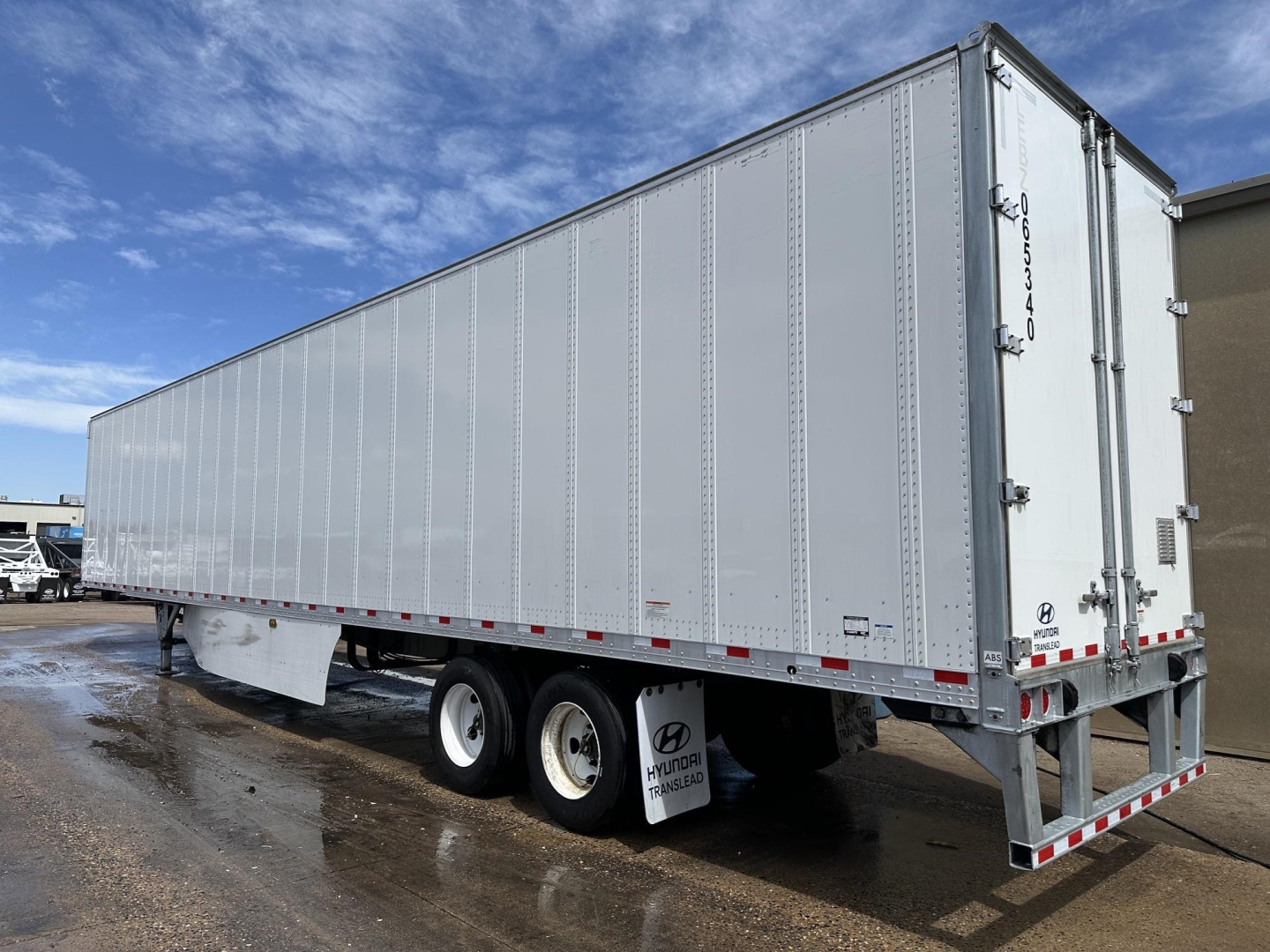 Tri-axle Hyundai dry van trailer with aluminum roof and rear swing doors, side view showing riveted aluminum panels, white reflective tape along lower edge, rear bumper and mud flaps.