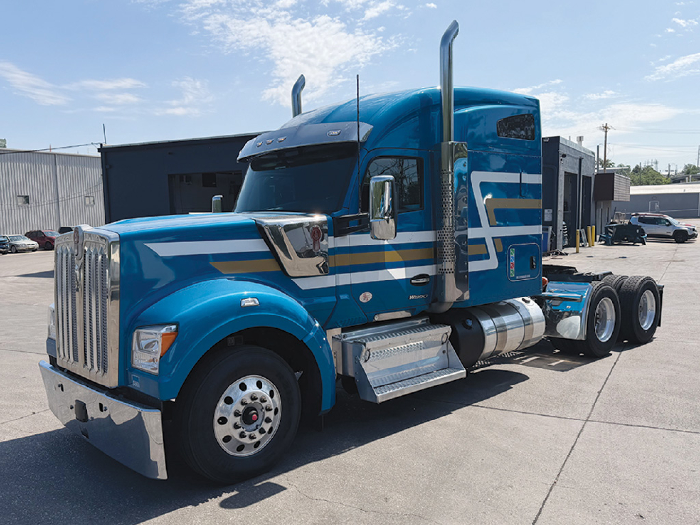 Kenworth W-990 tractor from side angle showing blue cab with chrome exhaust stacks and dual rear axles.