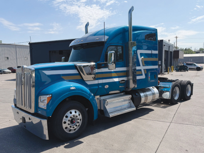 Kenworth W-990 tractor from side angle showing blue cab with chrome exhaust stacks and dual rear axles.