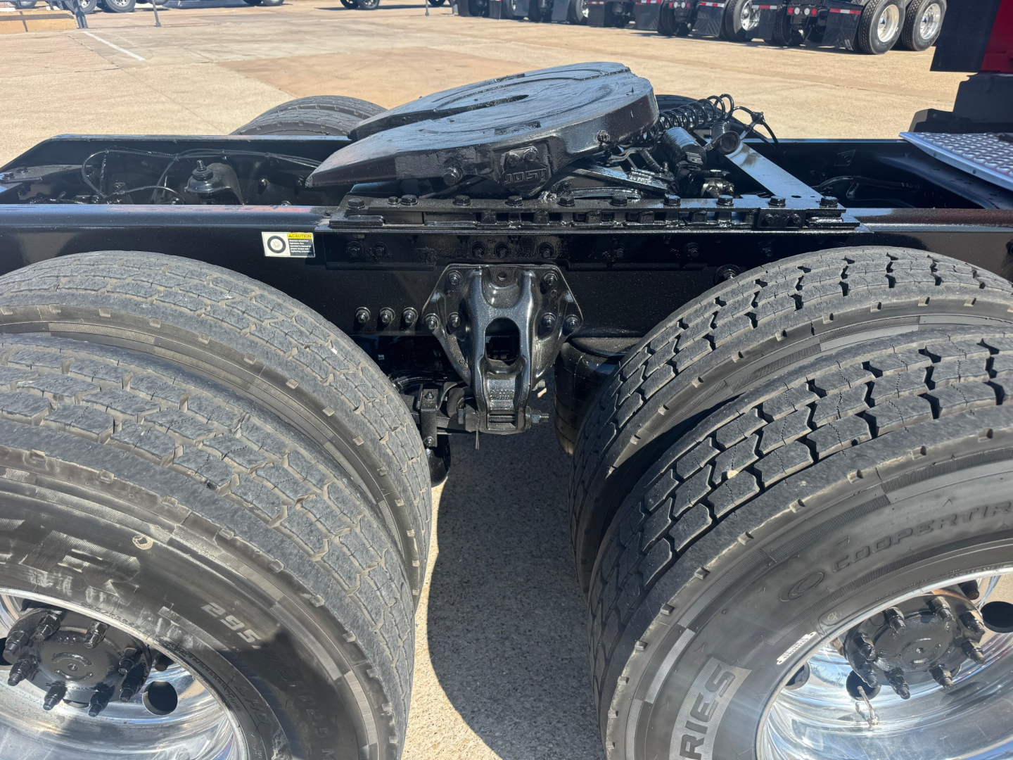 Kenworth T680 chassis cab showing dual rear axles and fifth wheel mounting with fuel and air lines visible.