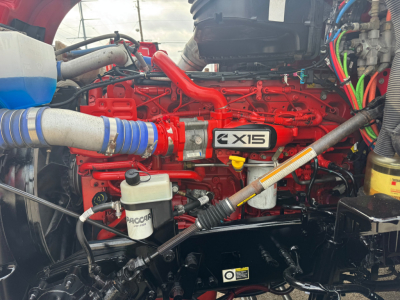 Kenworth T680 engine bay with red Cummins X15 label visible and various hoses and reservoirs.