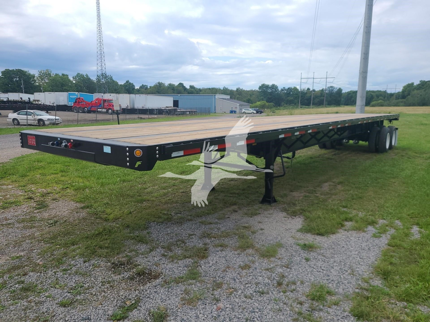Fruehauf flatbed trailer showing long deck and dual rear axles with jack and toolbox.