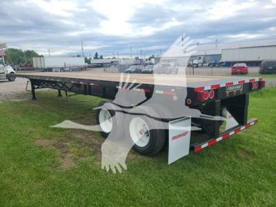 Fruehauf steel flatbed trailer with dual rear axles, black color, white mudflaps, and reflective stripes. Side shows flatbed, rear has taillights and Fruehauf branding.