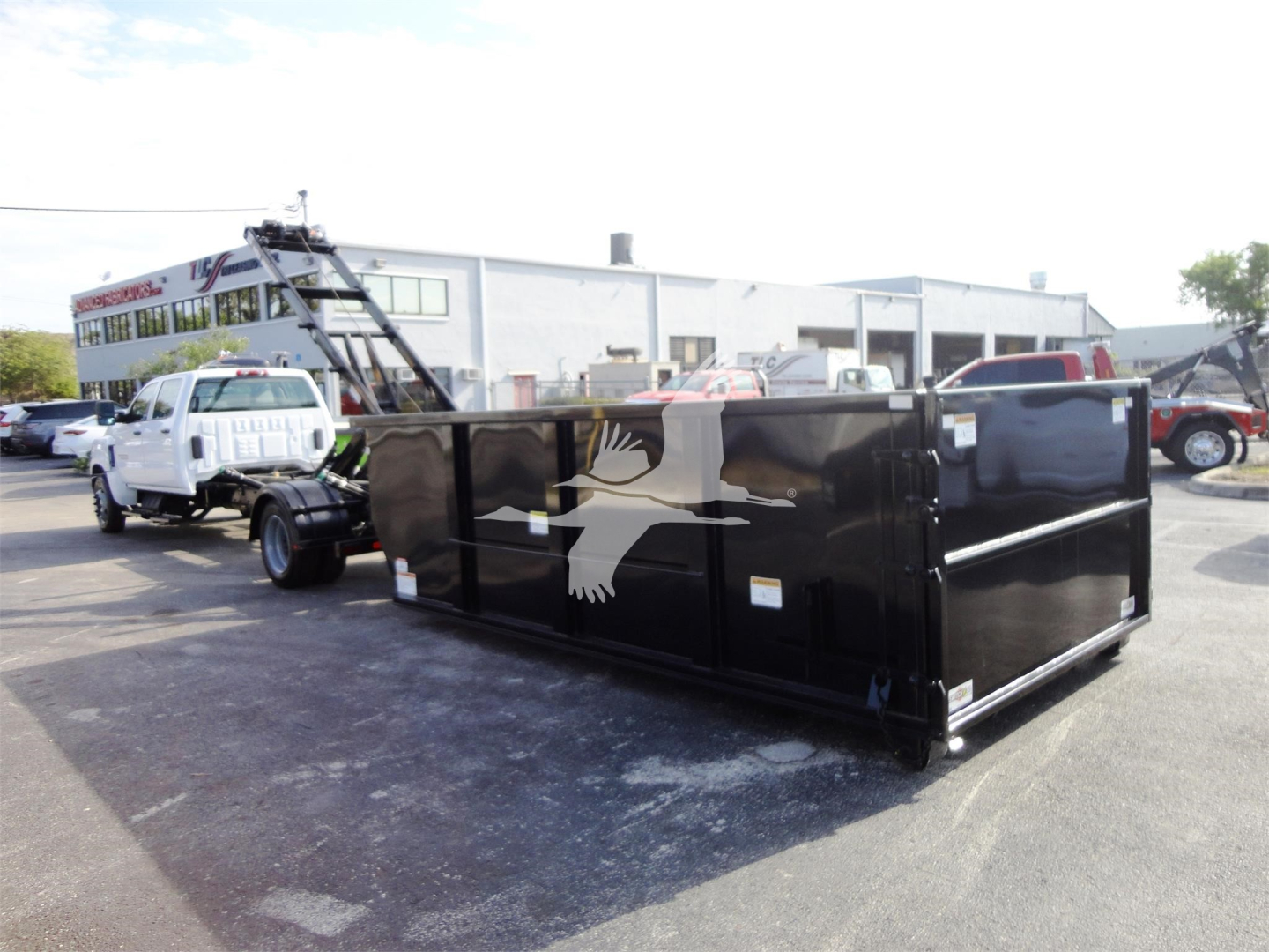 New 2023 Chevrolet Silverado 5500HD roll-off truck with black Stake/Dump body and white eagle silhouette logo, showcased in lot.
