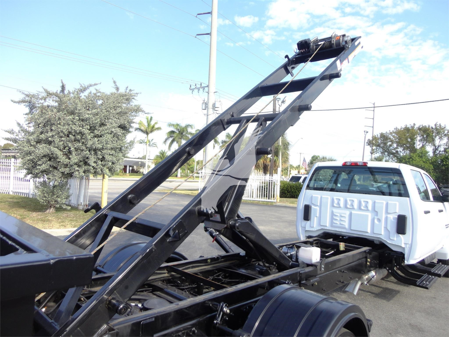 Truck chassis with hydraulic tipping mechanism and white Silverado cab profile, roll-off body frame visible