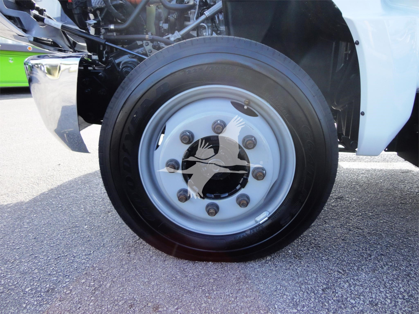 Wheel assembly of a 2023 Chevrolet Silverado 5500HD roll-off truck showing front wheel with silver rim and black tire.