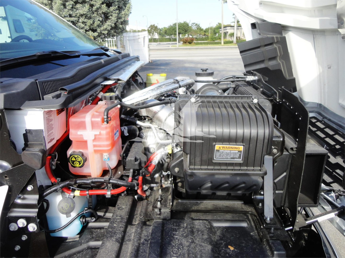 Chevrolet Silverado 5500HD engine bay with red coolant reservoir, blue windshield washer bottle, and black air intake housing visible under open hood.