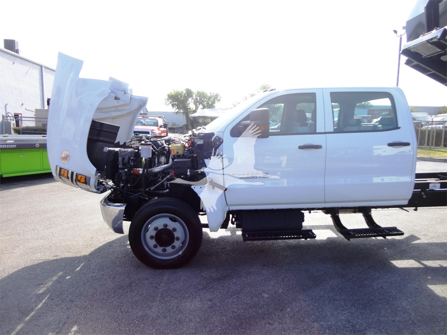 Chevrolet Silverado 5500HD roll-off truck side view with hood open exposing engine bay and front wheel.