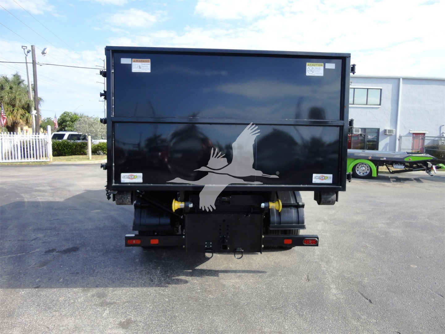 Truck bed of a new 2023 Chevrolet Silverado 5500HD rolloff dump with graphic design on tailgate showing white hands reaching; rear view with bumper and hitch.