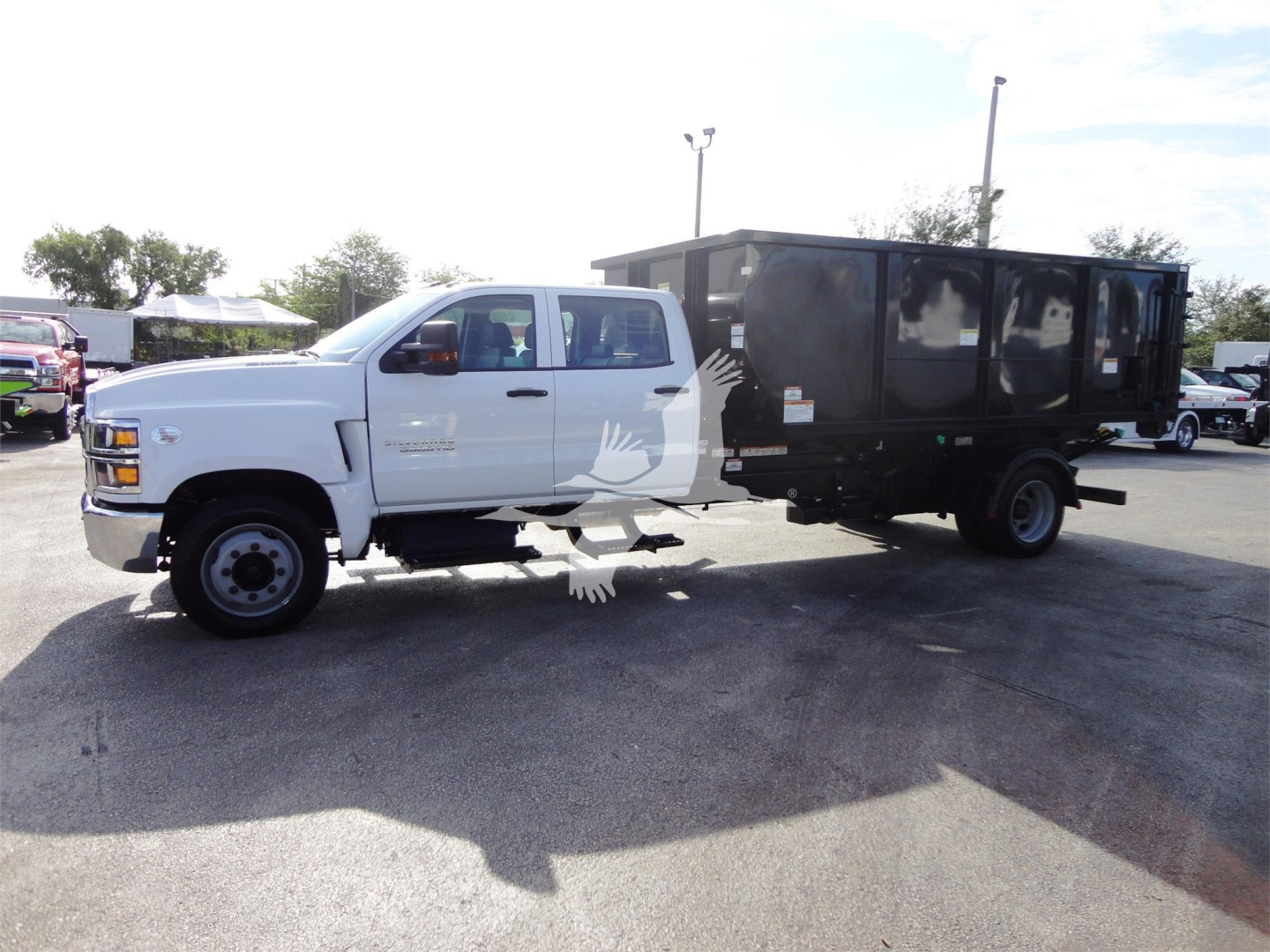 Chevrolet Silverado 5500HD truck with black roll-off bed attached, side view showing cab and cargo container.