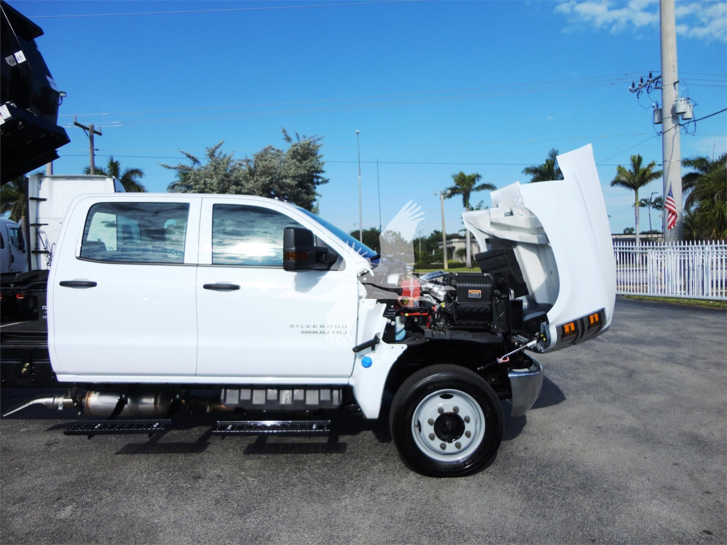 2023 Chevrolet Silverado 5500HD truck side view with hood open showing front engine bay and roll-off bed components.
