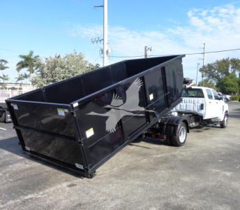 Black dump bed attached to a white Chevrolet Silverado 5500HD truck in a dealership lot; stock number J82601; roll-off category; new vehicle.