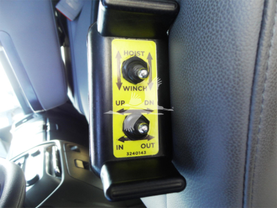 Winch control panel with up/down arrows and IN/OUT labels on yellow plate inside 2023 Chevrolet Silverado 5500HD rolloff truck