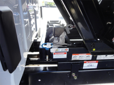 Truck hitch area with hydraulic lift mechanism and warning labels on a Silverado 5500HD truck.