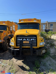 Front view of a yellow 2014 Mack garbage truck with large grille, bumper guard, and side mirrors.