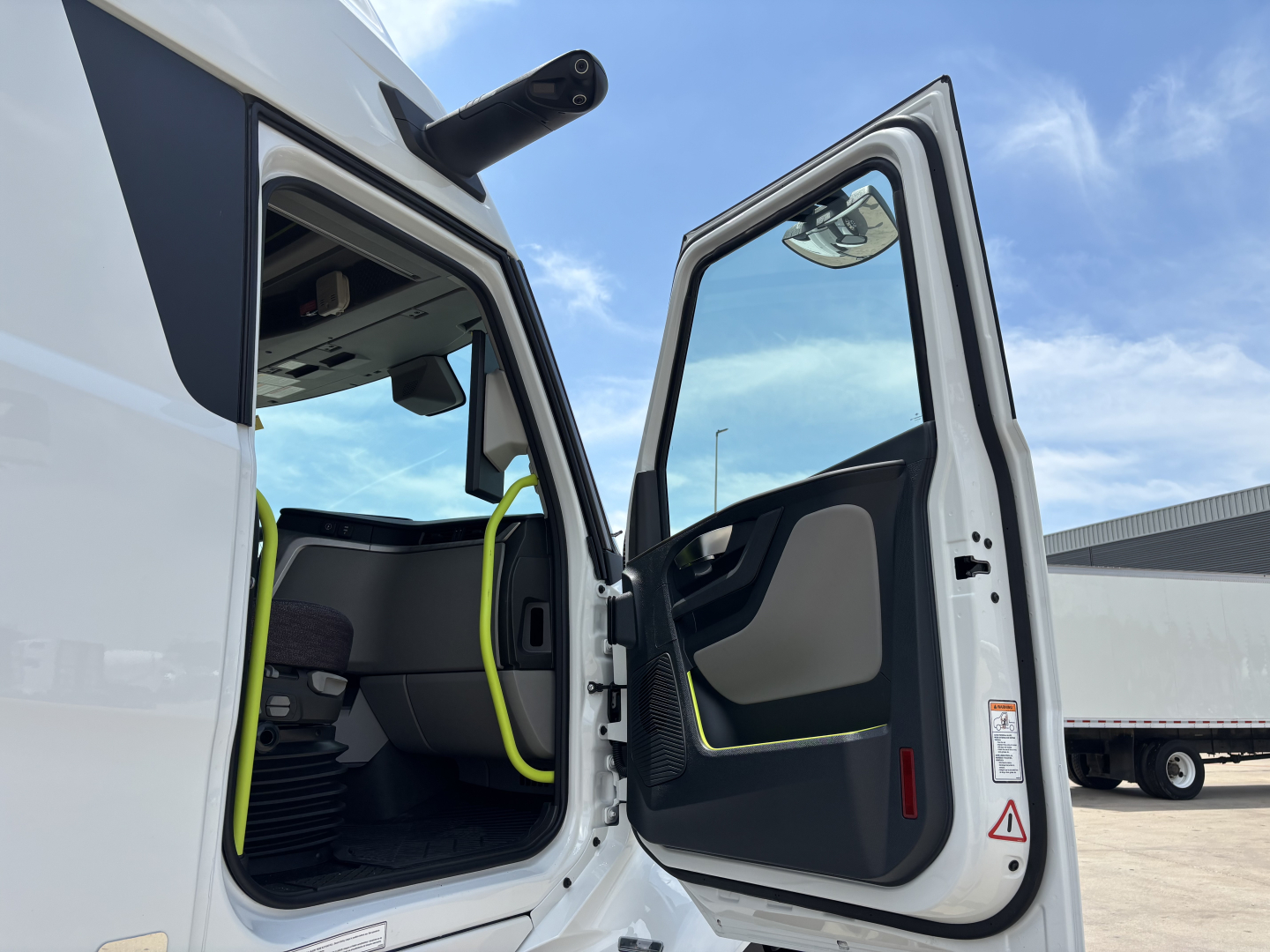 Volvo VNL64T860 truck with open driver door showing interior seating and yellow safety rails.