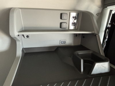 Cab interior view of a 2027 Volvo VNL64T860 showing overhead power outlets and a storage tray.
