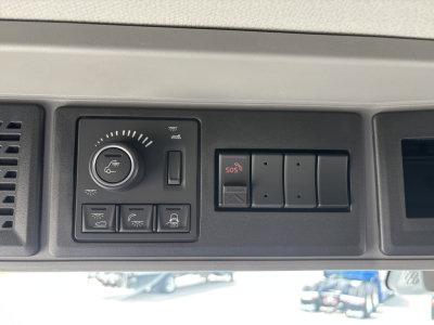 Volvo VNL64T860 dash panel showing circular climate/air control and multiple switches, including SOS button and hazard-like controls.