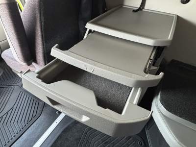Open storage drawers in a Volvo VNL64T860 sleeper cab showing multiple grey molded compartments and pull-out shelves.