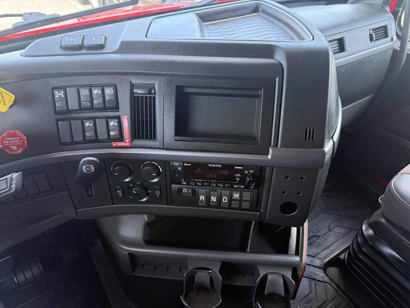 Volvo VNL64T860 dashboard interior showing steering wheel, control switches, radio, gear shifter panel, and central storage.