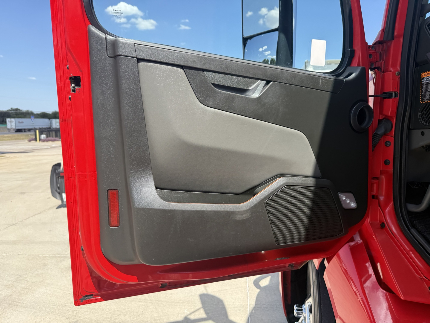 Truck door interior panel of a Volvo VNL cabin showing gray and black door trim, window, and handle.