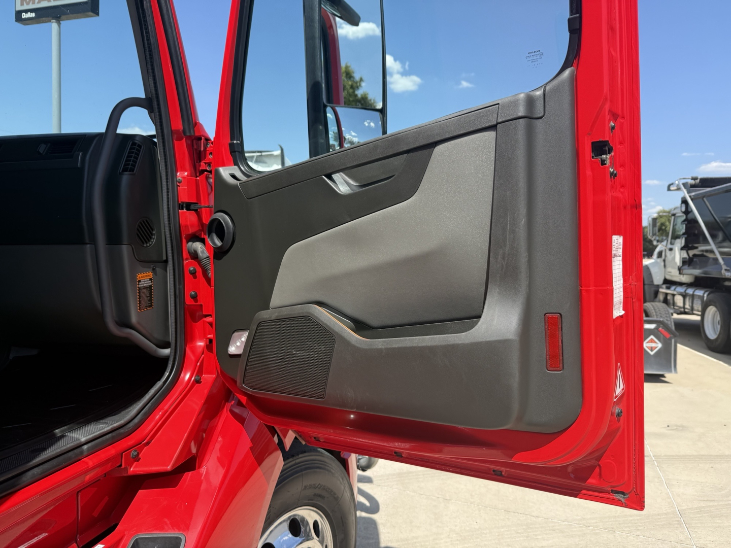Door panel and open cab of a red Volvo VNL64T860 truck showing interior door trim and entry area.