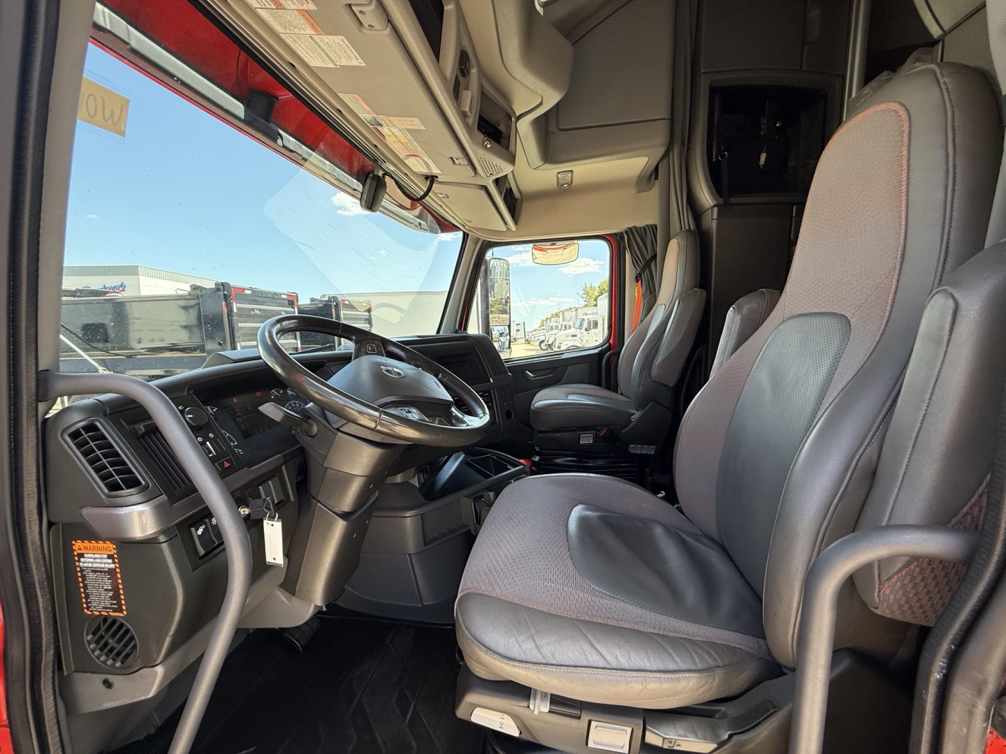 Volvo VNL truck interior showing steering wheel, driver seat, and dashboard from the cab entrance.