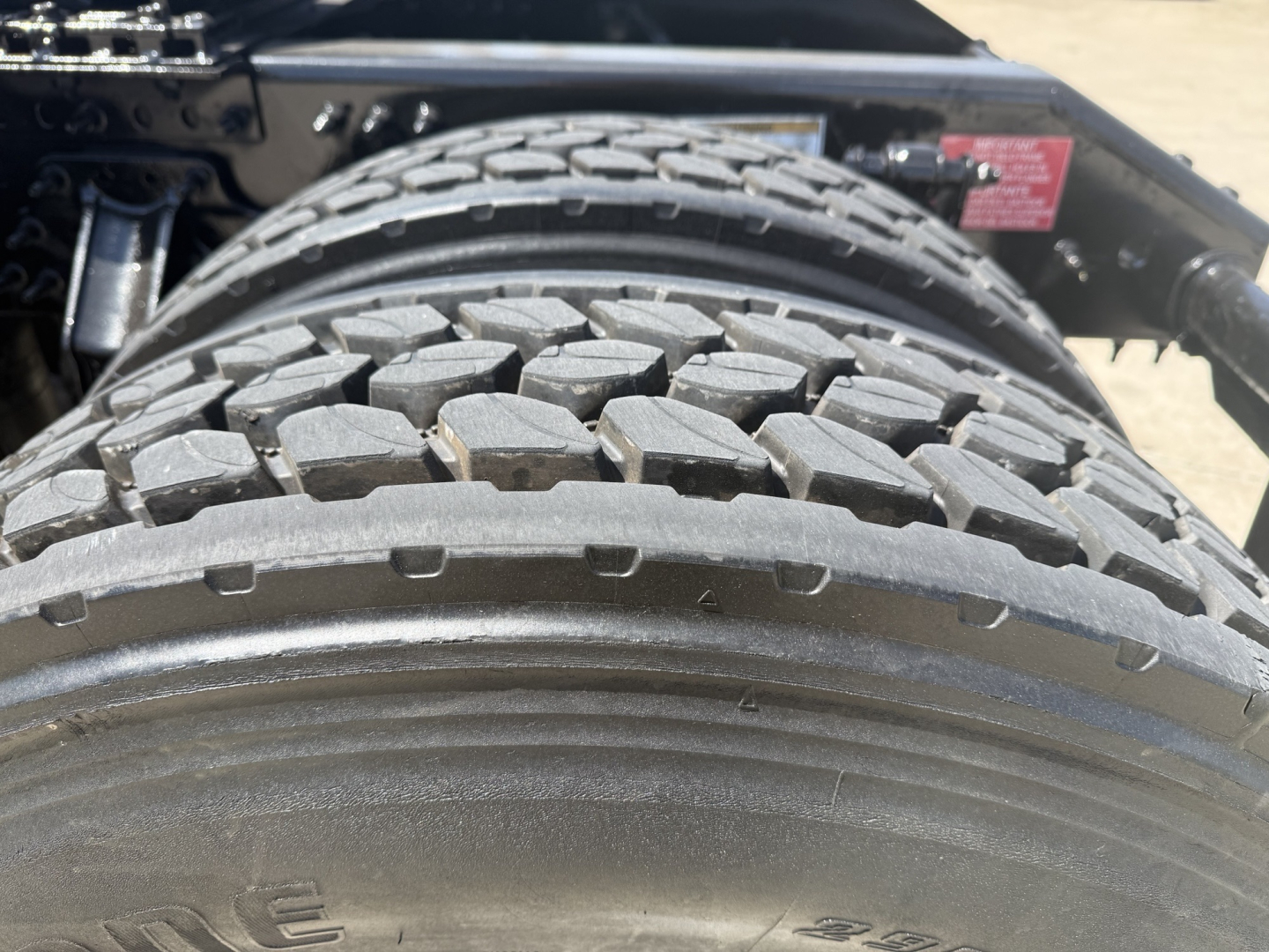 View of Volvo VNL64T860 rear dual tires and chassis frame showing rugged tread pattern and wheel well.
