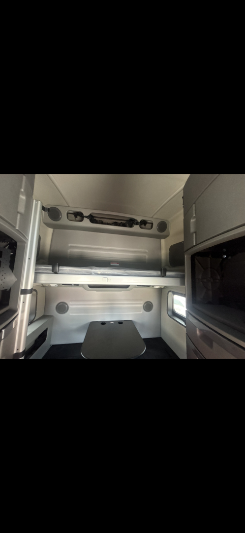 Volvo VNL64T860 sleeper cab interior showing bunk area and overhead storage, cabin walls, and window.
