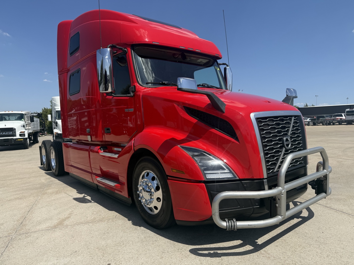 Volvo VNL64T860 tractor in red color with front bumper guard and chrome grille. View shows passenger side with sleeper cab and large front wheels.