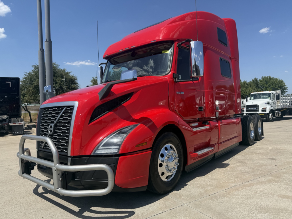 Volvo VNL64T860 tractor in red with chrome bumper guard and sleeper cab, displaying front grille and side mirrors.