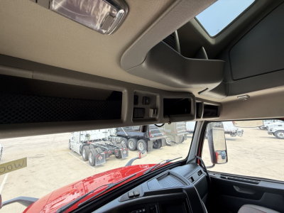 Cab interior of a Volvo VNL truck showing overhead dash area, control panels, and window with exterior yard visible.