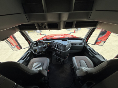 Cab interior of a Volvo VNL sleeper truck showing driver and passenger seats, dashboard, steering wheel, and center console.
