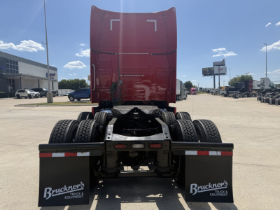 Truck rear view of a 2024 Volvo VNL64T860 sleeper tractor showing chassis and fifth wheel, with red cab high at back and dual rear axles.