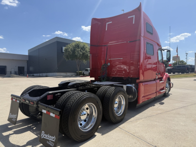  Volvo VNL64T860 tractor rear and cab in red with triple axles and sleeper, showing rear wheels and fifth wheel area.