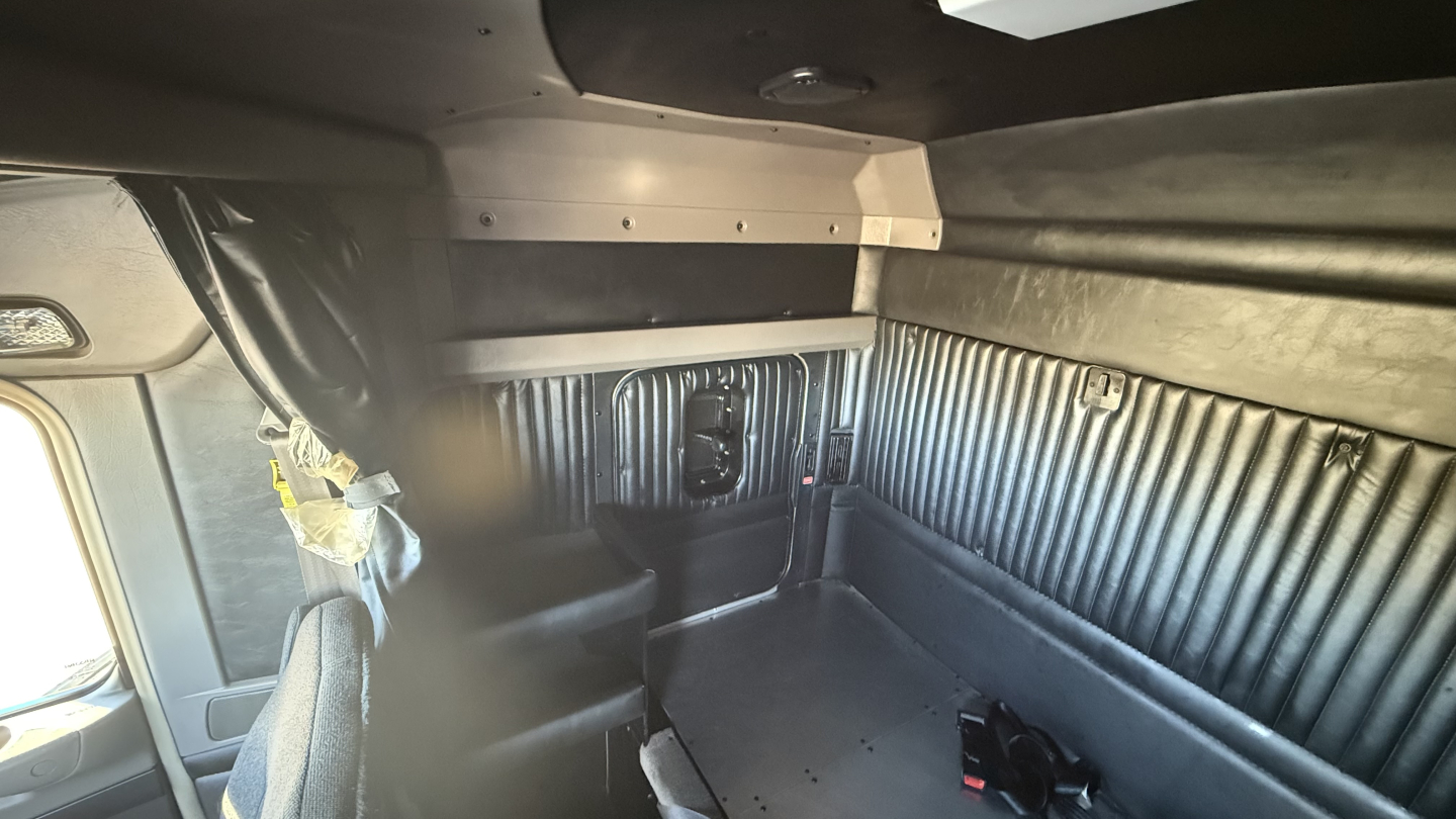 Kenworth W900 truck cab interior showing sleeper area with ribbed side panels and storage compartments.