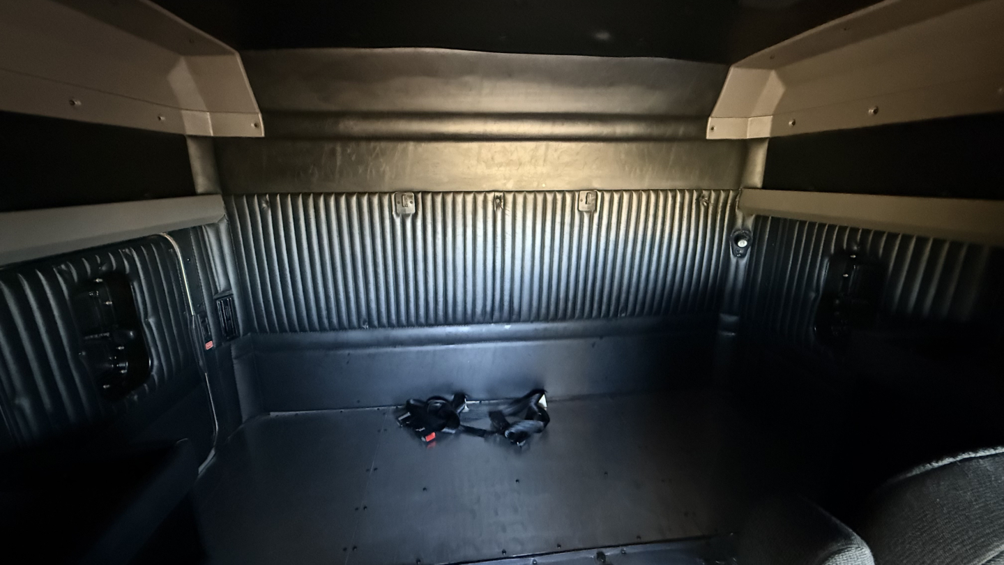 Kenworth W900 sleeper cab interior cargo area showing metal ribbed wall panels and tiedowns, with dark floor and side panels.