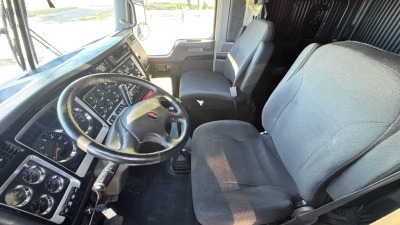 Kenworth W900 truck cabin interior showing steering wheel, dash gauges, front seats and passenger seat.